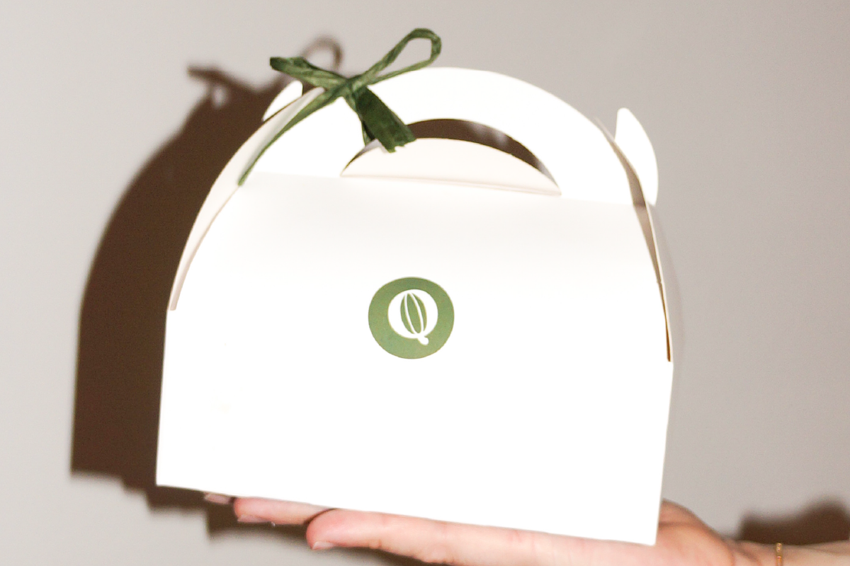 prod-29 boîte de pâtisserie blanche avec un logo vert au centre, carac